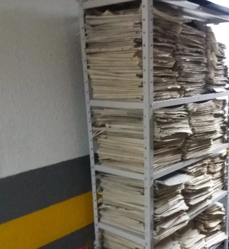 Acervo antes da organização: pilhas de papéis empilhadas em prateleira